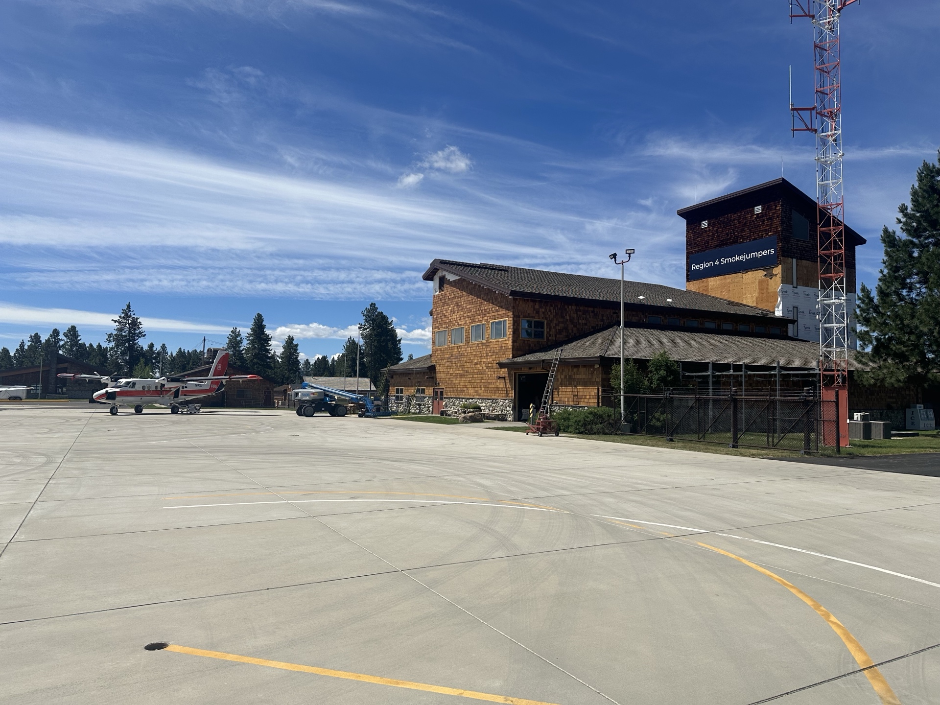 After photo of McCall Smoke Jumper Base — wide tarmac view showing Region 4 Smokejumpers tower and main building with completed cedar shake siding