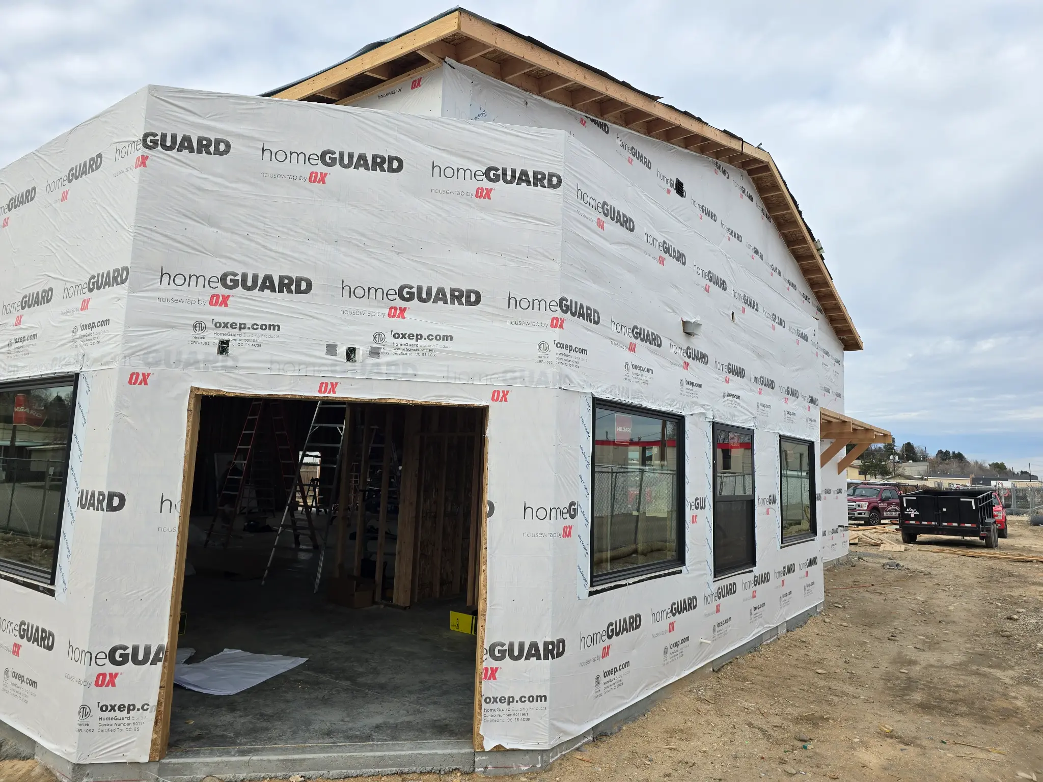 Before photo of commercial building front corner showing the office entry opening and warehouse windows wrapped in HomeGuard housewrap