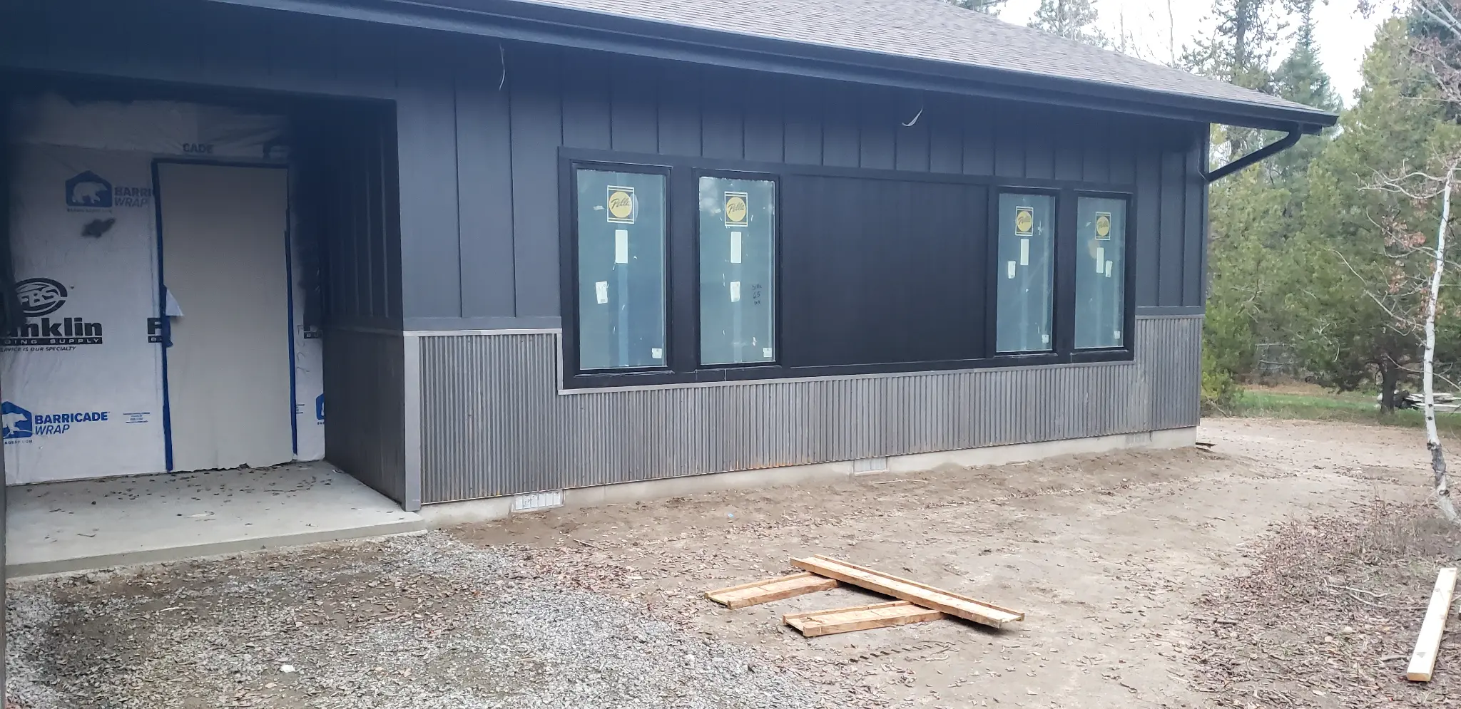After photo of House 1 with dark board-and-batten siding, black-framed windows, corrugated lower accent siding, and cleaner exterior lines