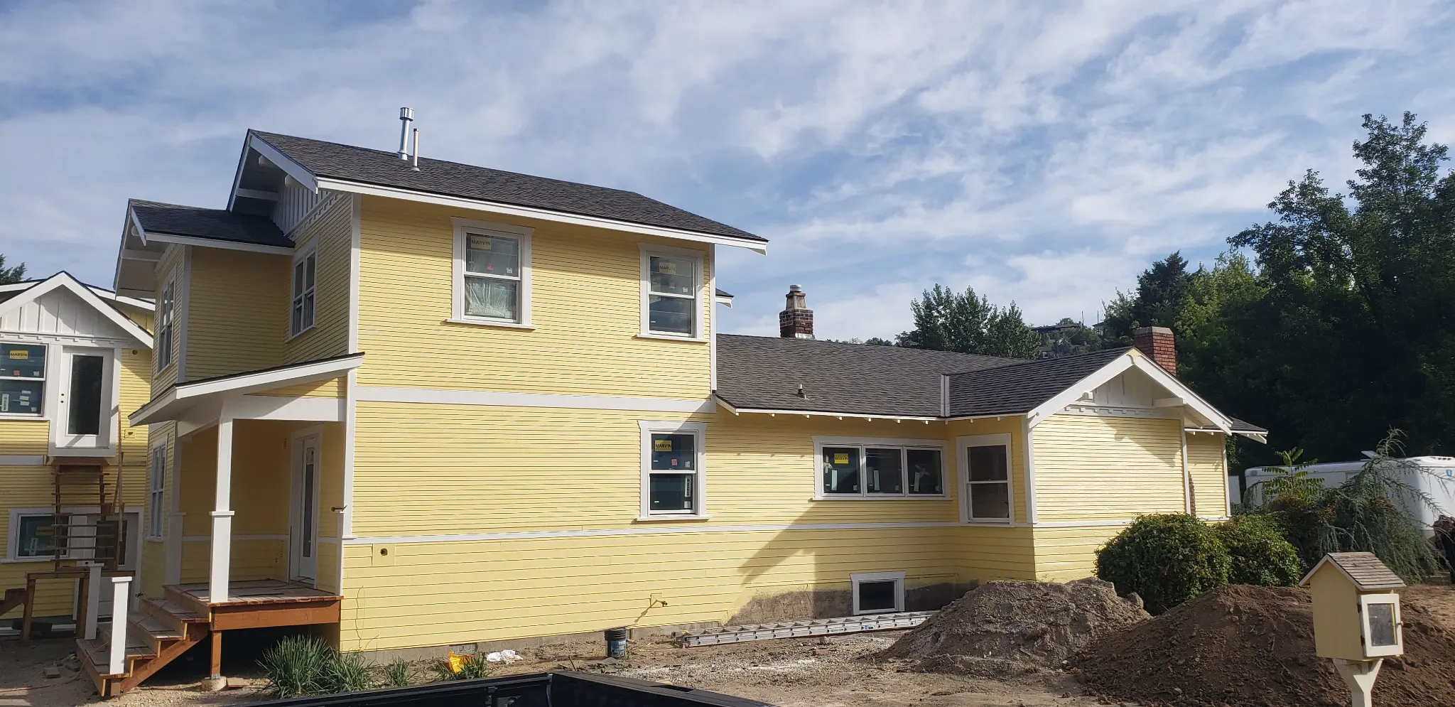 After photo of House 2 with yellow lap siding, white trim, new windows, and a clean completed exterior profile